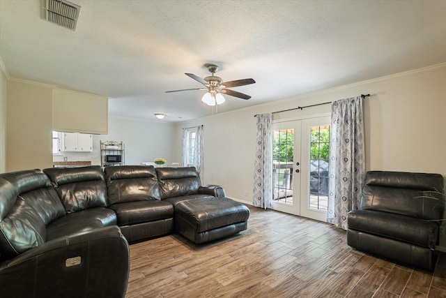 living area with wood finished floors, a ceiling fan, baseboards, and crown molding