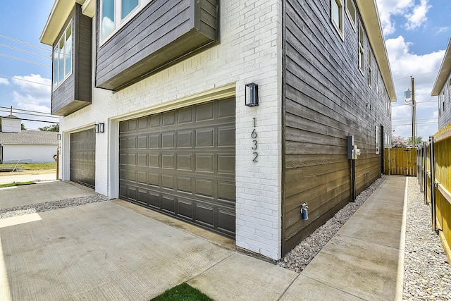 garage with concrete driveway and fence