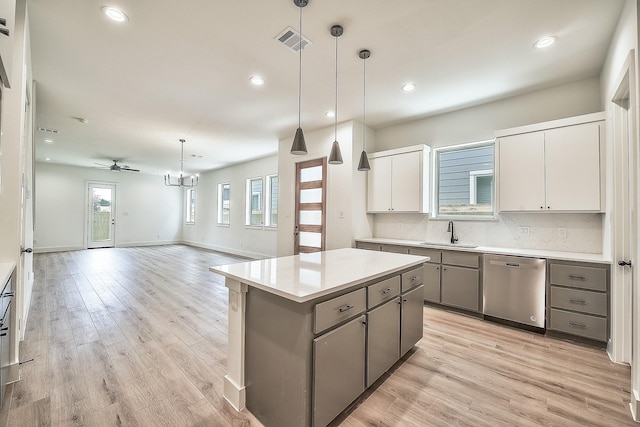 kitchen featuring visible vents, a center island, a sink, dishwasher, and gray cabinetry