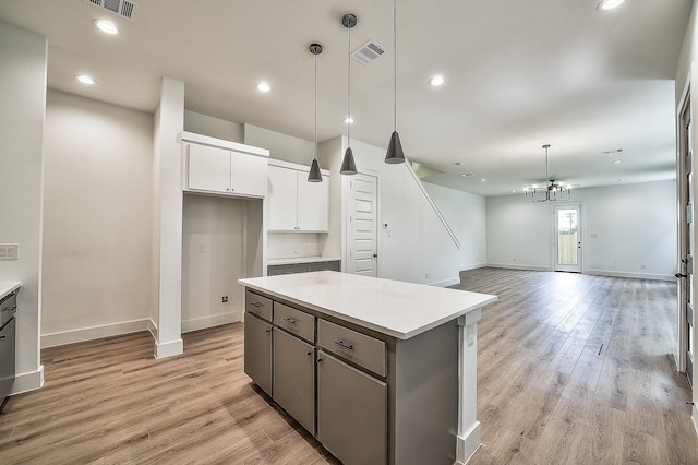 kitchen with baseboards, light wood finished floors, white cabinetry, and visible vents