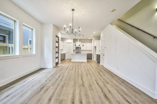 unfurnished living room featuring light wood-style floors, recessed lighting, baseboards, and a chandelier