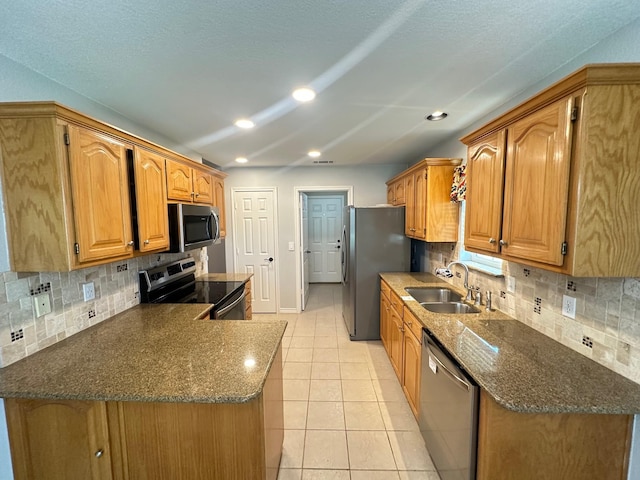 kitchen with tasteful backsplash, a sink, dark stone countertops, stainless steel appliances, and light tile patterned flooring