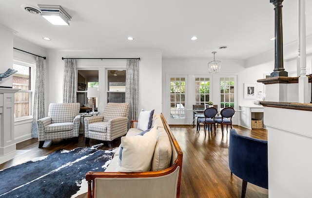 living room featuring recessed lighting, an inviting chandelier, ornamental molding, and wood finished floors