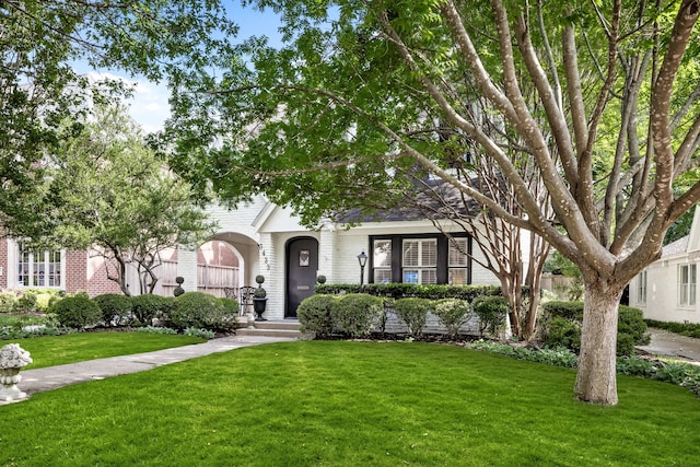 obstructed view of property featuring brick siding and a front lawn