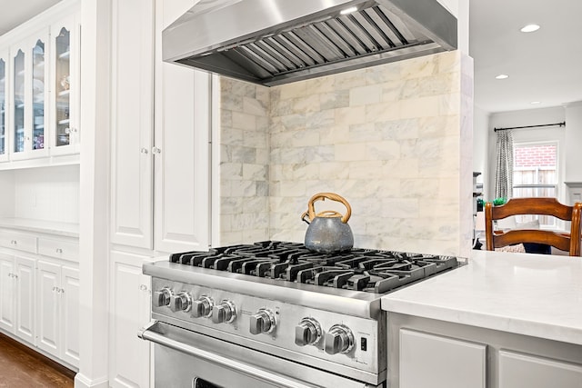 kitchen featuring light countertops, stainless steel range, white cabinets, custom exhaust hood, and glass insert cabinets