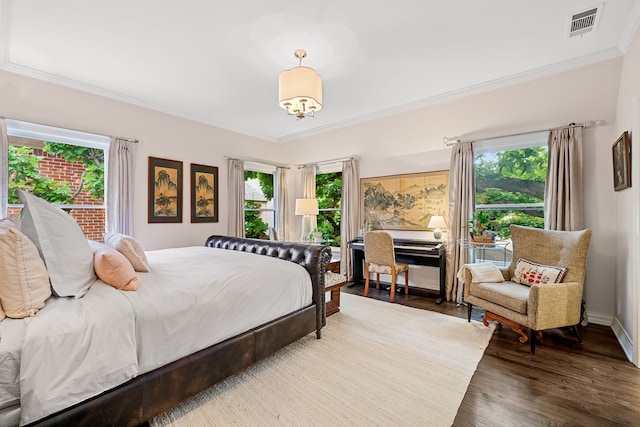 bedroom with visible vents, crown molding, wood finished floors, baseboards, and a chandelier
