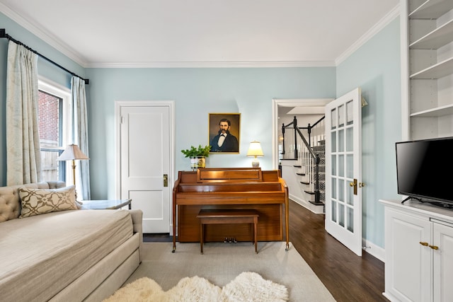 living area featuring ornamental molding, wood finished floors, and stairway