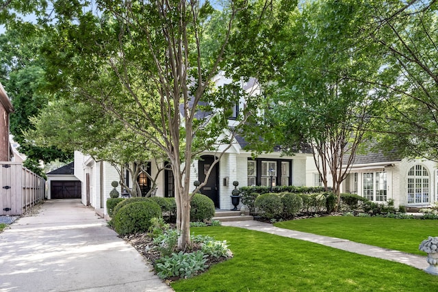 obstructed view of property featuring an outdoor structure, a garage, a front lawn, brick siding, and driveway