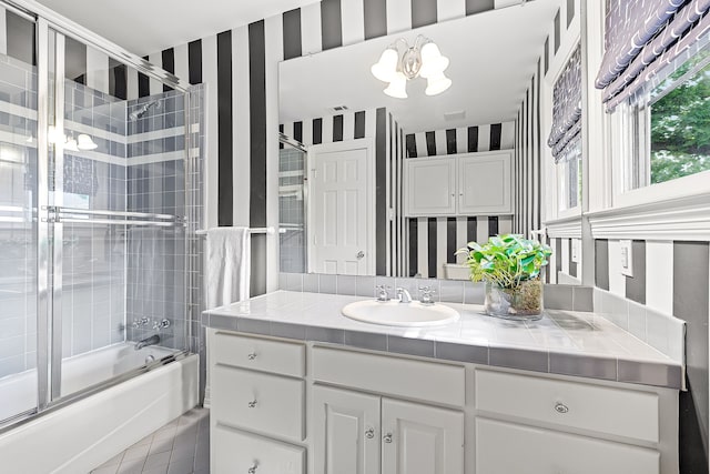 bathroom with tile patterned flooring, vanity, a chandelier, wallpapered walls, and bath / shower combo with glass door