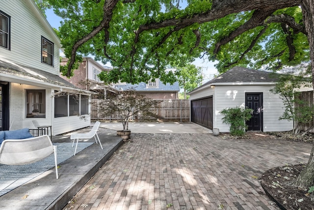 view of yard with driveway, an outbuilding, a sunroom, a patio area, and fence