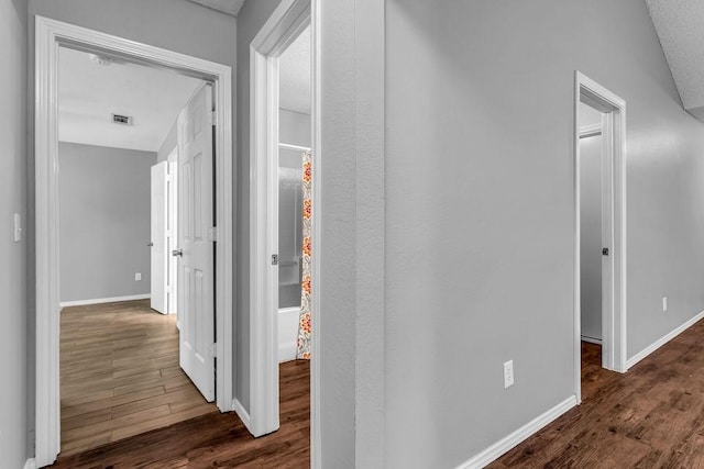 hall featuring baseboards, visible vents, and wood finished floors