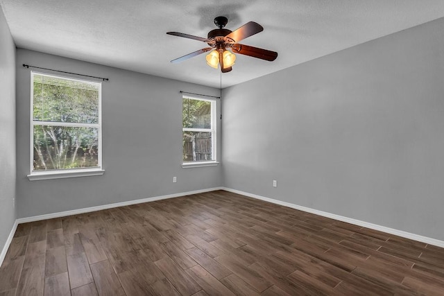 empty room with a textured ceiling, ceiling fan, baseboards, and dark wood-type flooring