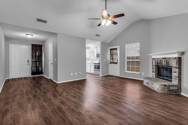 unfurnished living room with a fireplace, a ceiling fan, lofted ceiling, dark wood-type flooring, and visible vents