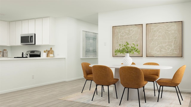 dining area featuring light wood-style floors and baseboards