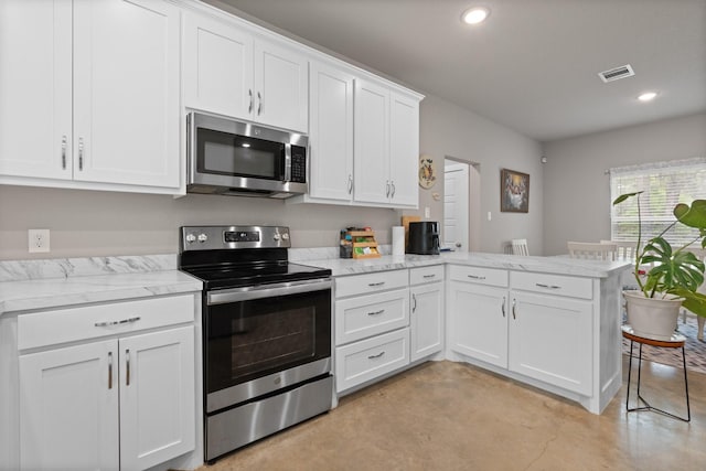 kitchen with visible vents, appliances with stainless steel finishes, white cabinets, a peninsula, and concrete floors