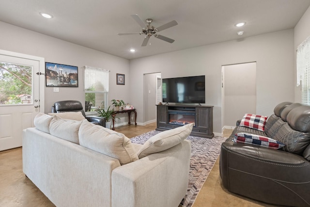 living room featuring recessed lighting, a glass covered fireplace, ceiling fan, and baseboards