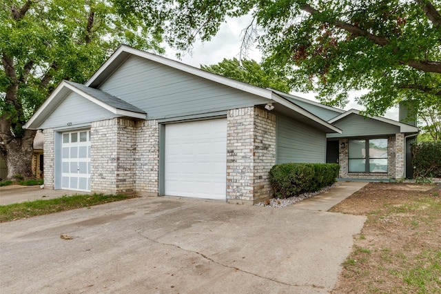 ranch-style home with an attached garage, a chimney, brick siding, and concrete driveway