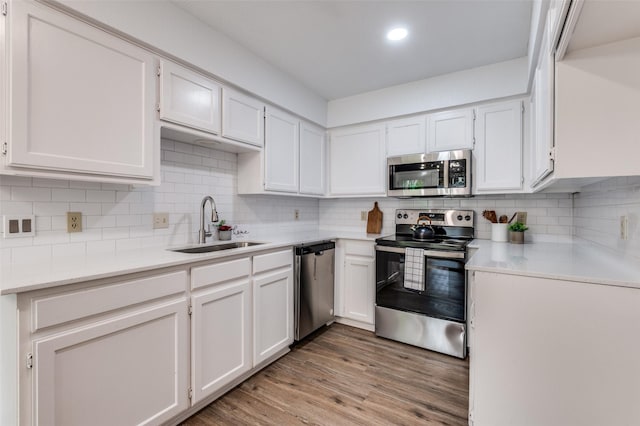 kitchen featuring white cabinets, stainless steel appliances, a sink, and tasteful backsplash
