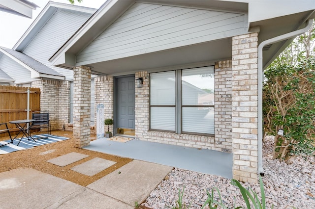 doorway to property with brick siding and fence