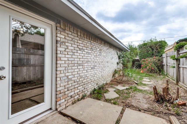 view of side of property with fence and brick siding