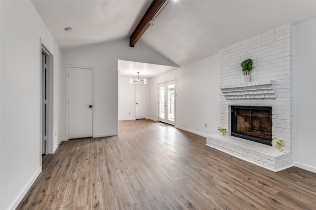 unfurnished living room with lofted ceiling with beams, baseboards, a fireplace, and wood finished floors
