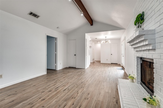 unfurnished living room with visible vents, a fireplace, light wood-style floors, lofted ceiling with beams, and a notable chandelier