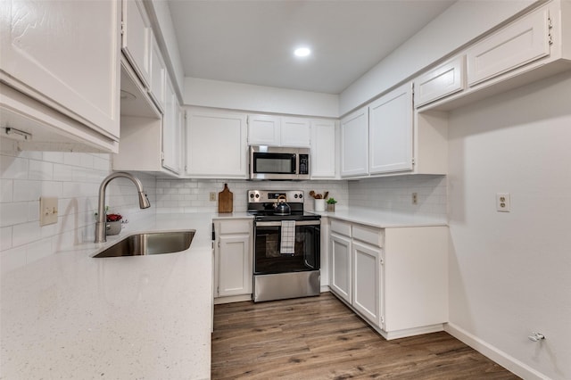 kitchen featuring dark wood-style flooring, white cabinetry, a sink, appliances with stainless steel finishes, and backsplash