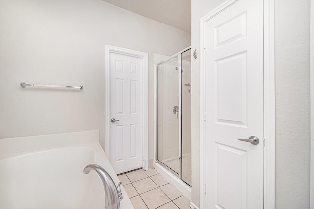 bathroom featuring tile patterned flooring, a shower stall, and a garden tub