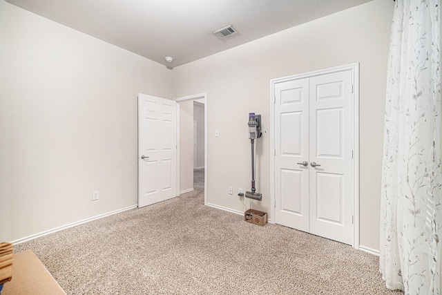 unfurnished bedroom with baseboards, carpet, a closet, and visible vents