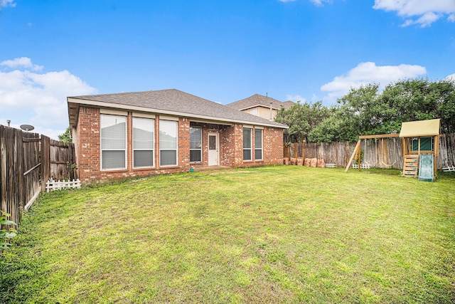 back of property featuring a lawn, brick siding, and a playground