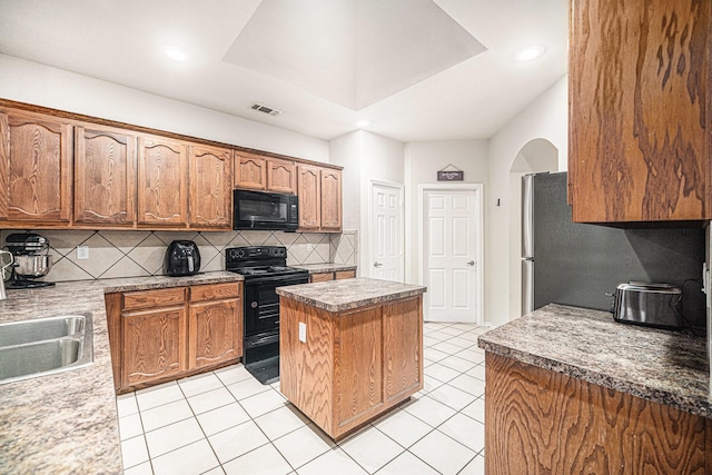 kitchen featuring visible vents, a center island, tasteful backsplash, a sink, and black appliances