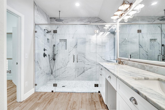 bathroom featuring double vanity, wood finished floors, recessed lighting, a sink, and a marble finish shower