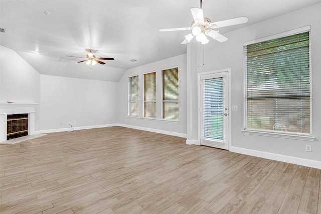 unfurnished living room featuring a ceiling fan, light wood finished floors, a glass covered fireplace, and vaulted ceiling