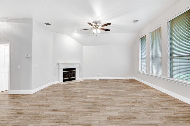 unfurnished living room with a ceiling fan, visible vents, light wood-style flooring, and vaulted ceiling