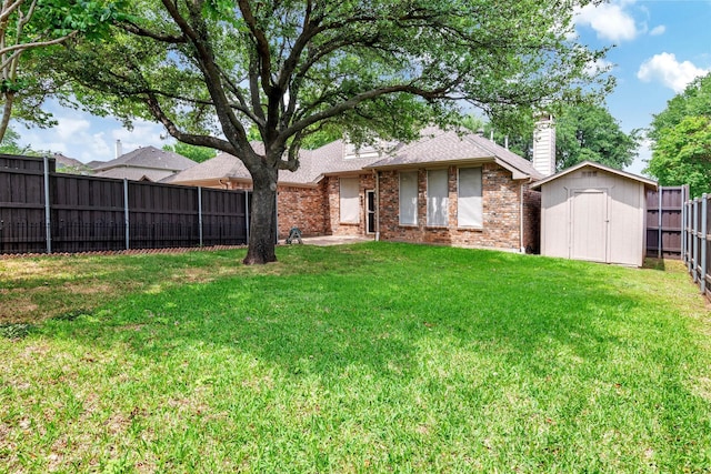 rear view of property with a fenced backyard, a chimney, brick siding, a storage shed, and a yard
