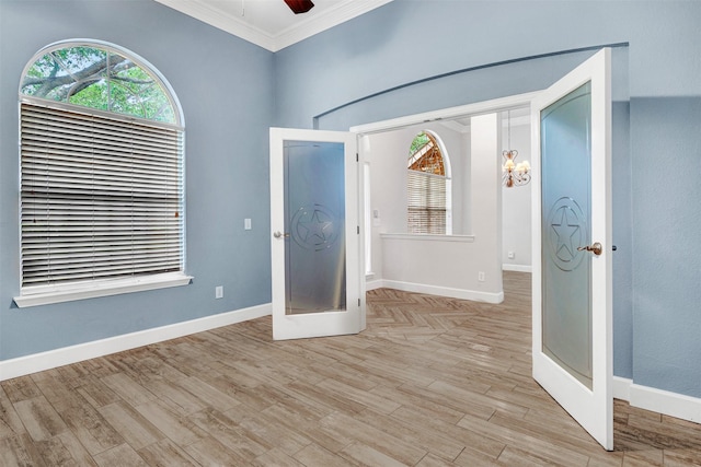 foyer entrance with crown molding, baseboards, ceiling fan with notable chandelier, and light wood-style floors