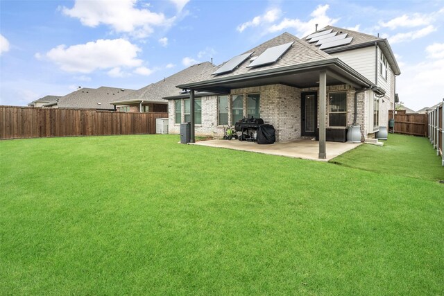 rear view of property featuring brick siding, a fenced backyard, roof with shingles, and a patio area