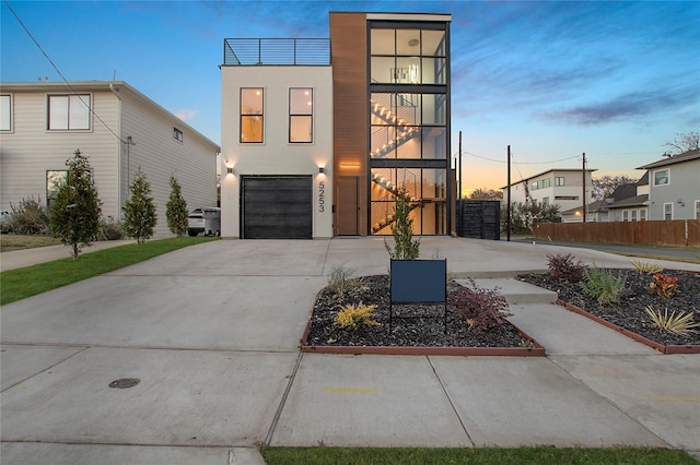 modern home with stucco siding, fence, driveway, and a garage