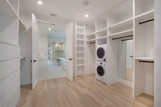 laundry room with stacked washer / drying machine, visible vents, a barn door, and laundry area