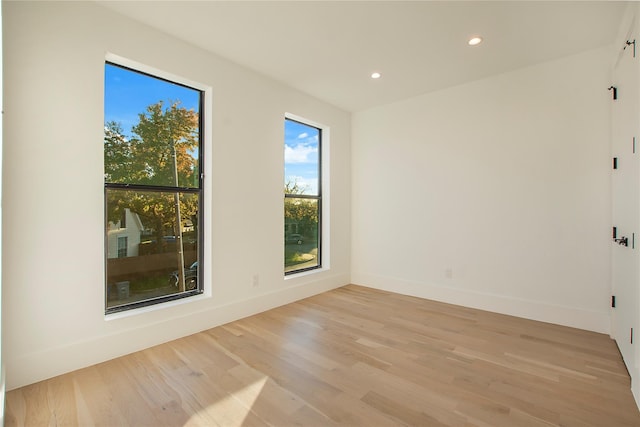 empty room with baseboards, light wood-type flooring, and recessed lighting