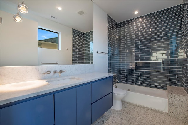 full bathroom featuring visible vents, double vanity, toilet, speckled floor, and a sink