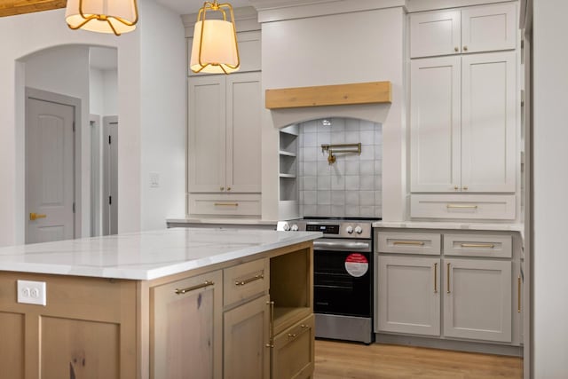 1900 County Road 1255, Savoy, TX 75479 - kitchen featuring a kitchen island, light stone countertops, light wood-type flooring, arched walkways, and stainless steel electric range oven