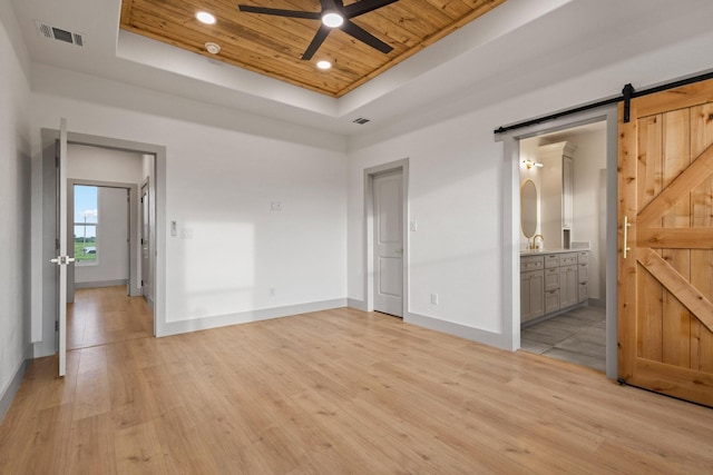1900 County Road 1255, Savoy, TX 75479 - unfurnished bedroom featuring visible vents, a barn door, wood ceiling, a tray ceiling, and light wood finished floors