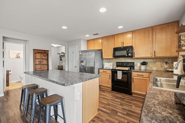 6336 Maritime St, Fort Worth, TX 76179 - kitchen featuring black appliances, a breakfast bar, tasteful backsplash, a sink, and dark countertops
