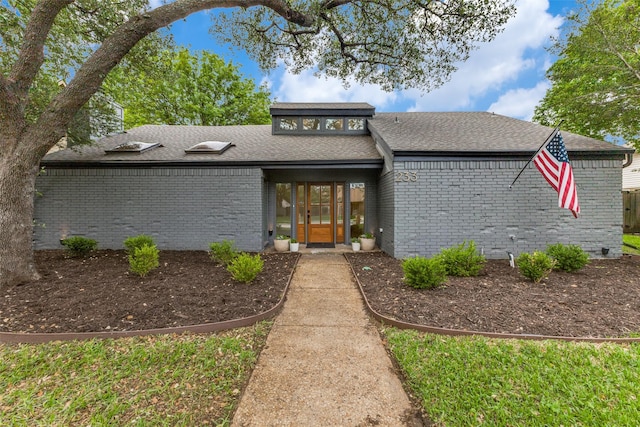 view of front of home featuring french doors, brick siding, and a shingled roof