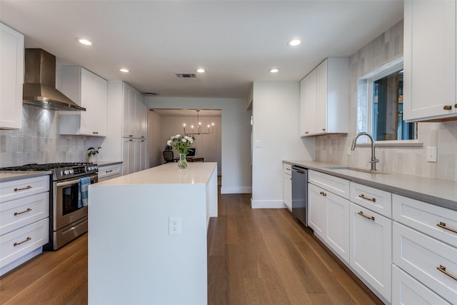 kitchen featuring a sink, wall chimney exhaust hood, a center island, stainless steel appliances, and visible vents