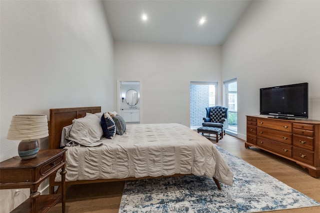 bedroom with connected bathroom, recessed lighting, high vaulted ceiling, and light wood finished floors