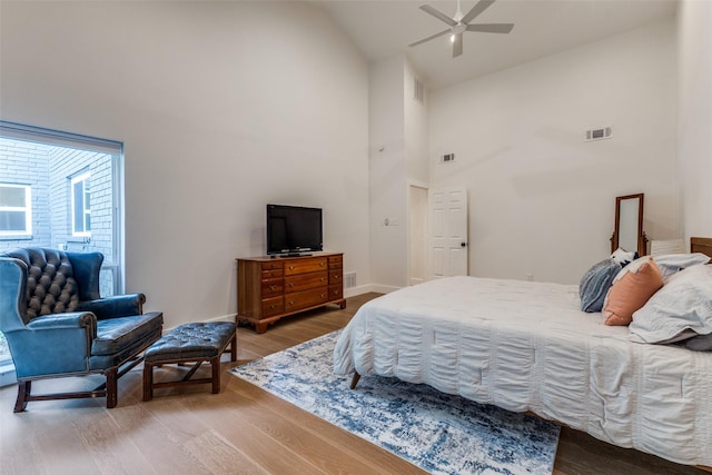 bedroom featuring visible vents, baseboards, wood finished floors, and high vaulted ceiling