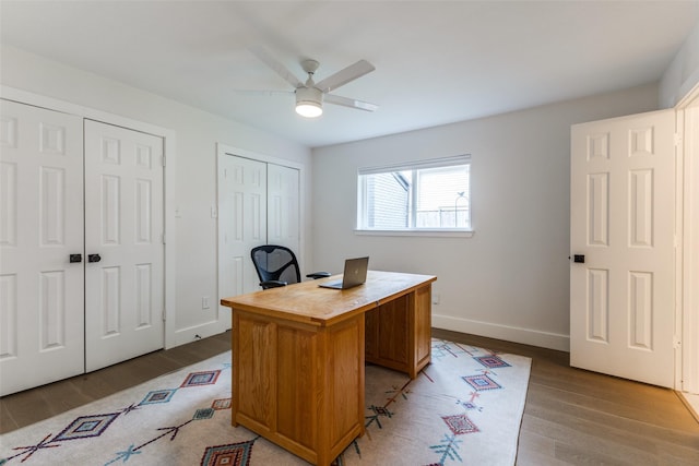 office with a ceiling fan, baseboards, and light wood-style flooring