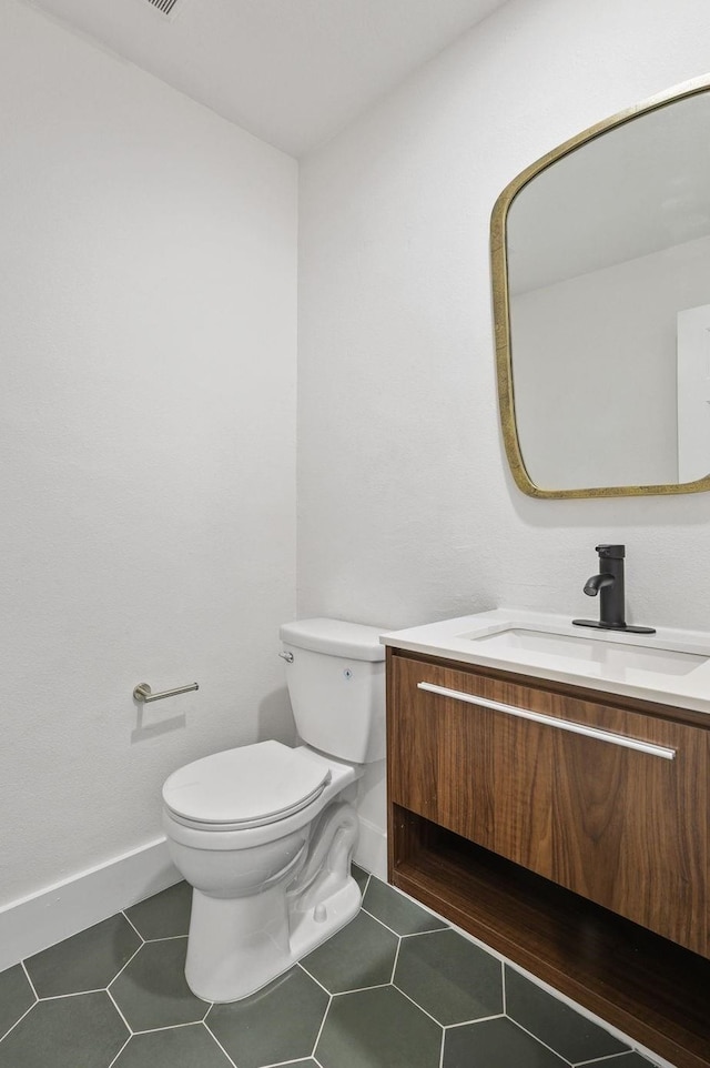 half bath featuring toilet, tile patterned floors, baseboards, and vanity